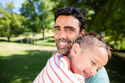 Father smiling while embracing his son in park