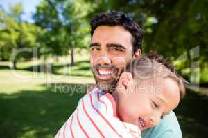 Father smiling while embracing his son in park