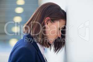 Worried businesswoman leaning her head on wall