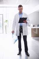 Doctor standing with clipboard in corridor