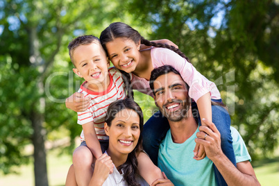 Portrait of parents carrying their children on shoulder in park