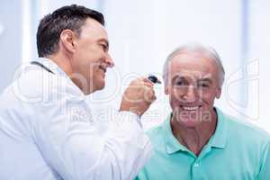 Doctor examining patients ear with otoscope