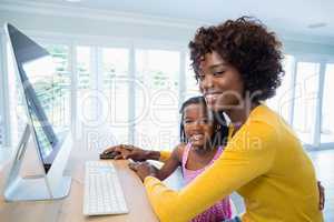 Mother and daughter using computer in living room at home