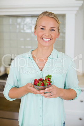 Beautiful woman holding glass of strawberry in kitchen