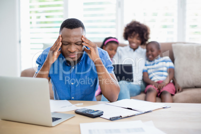 Worried man sitting at table with bills and laptop