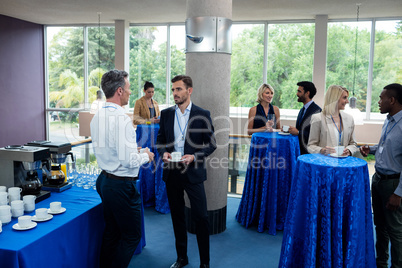 Business executives interacting with each other while having coffee