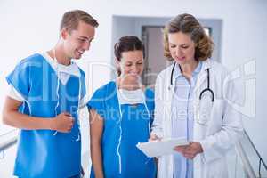 Doctors discussing with clipboard at hospital corridor