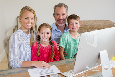 Happy family sitting at desk with computer