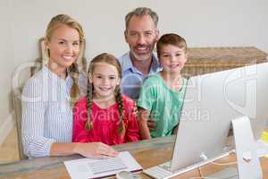 Happy family sitting at desk with computer