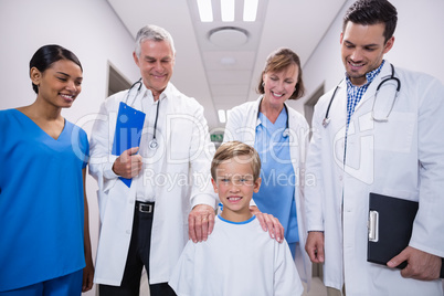 Doctors and nurse standing with boy patient in hospital corridor