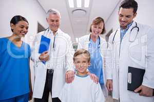 Doctors and nurse standing with boy patient in hospital corridor