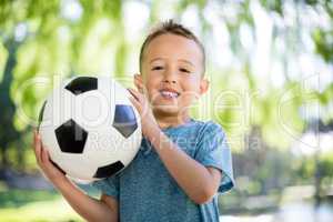 Portrait of boy holding a football in park