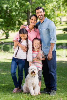 Portrait of happy family with their pet dog standing in park