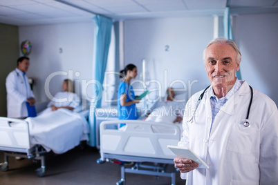 Portrait of male doctor smiling while holding digital tablet