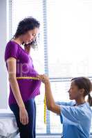 Doctor measuring pregnant womans belly in ward