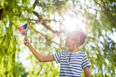 Boy holding small american flag in park