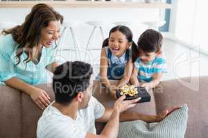 Father receiving a gift from his kids and wife in living room