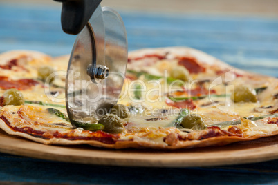 Delicious pizza served on pizza tray with cutter on pizza