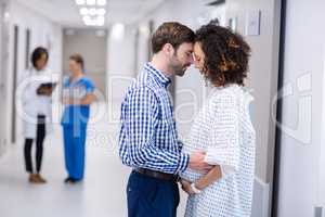 Man comforting pregnant woman in corridor