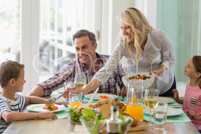 Mother serving food to family on dinning table