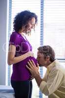 Man kissing pregnant womans belly in ward
