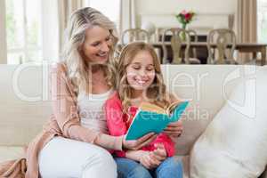 Mother and daughter reading a novel on the couch