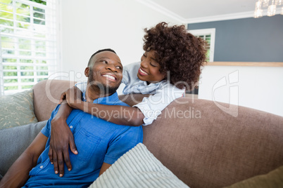 Happy couple embracing on sofa in living room at home