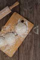 Rolling pin with pizza dough and flour on chopping board