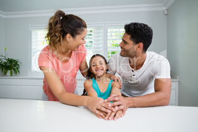 Parents and daughter interacting with each other in kitchen