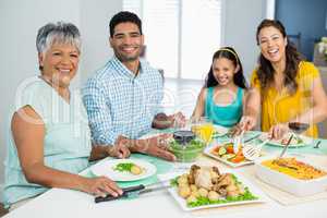 Happy multi generation family having meal on table at home