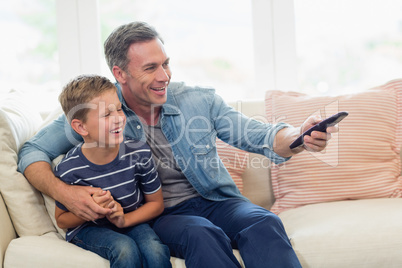 Happy father and son watching tv in living room