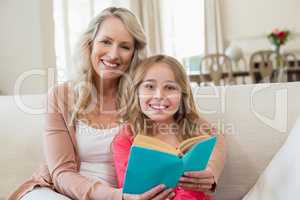 Mother and daughter reading a novel on the couch