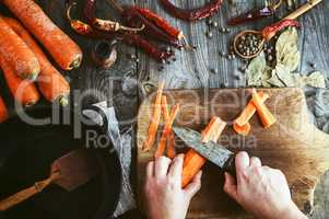 Two women's hands clean large carrots