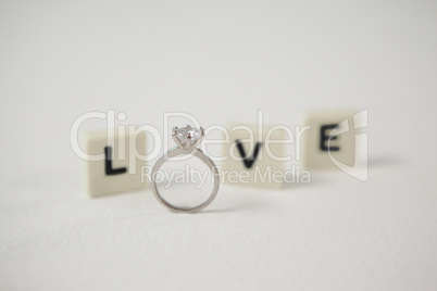 Diamond ring between white blocks displaying love message