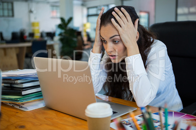 Upset female graphic designer looking at laptop