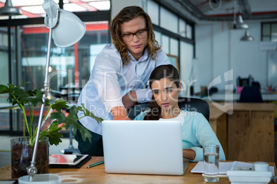 Business executives discussing over laptop