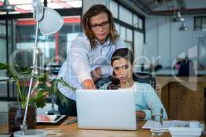 Business executives discussing over laptop