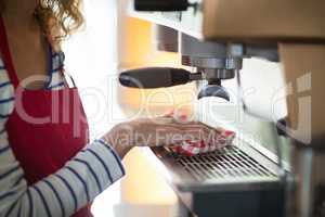 Waitress wiping espresso machine with napkin in cafÃ?Â©