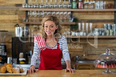 Portrait of smiling waitress standing at counter