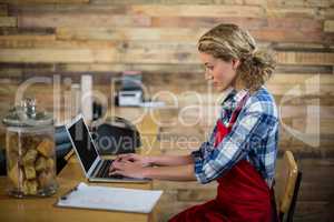 Waitress sitting at counter and using laptop in cafÃ?Â©