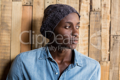 Thoughtful man standing against wooden wall