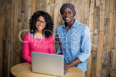 Smiling couple using laptop in cafÃ?Â©