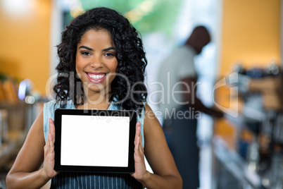 Portrait of smiling waitress showing digital tablet