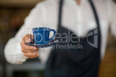 Mid-section of waiter offering a cup of coffee