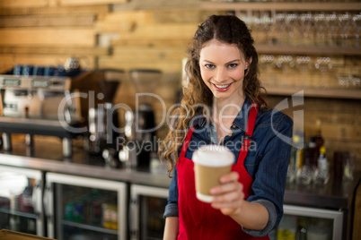 Smiling waitress serving a cup of coffee to customer in cafÃ?Â©