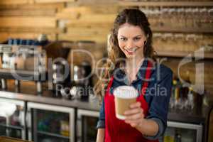 Smiling waitress serving a cup of coffee to customer in cafÃ?Â©