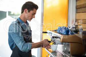 Waiter making cup of coffee at counter