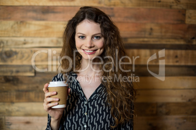 Smiling woman standing with disposable coffee cup in cafÃ?Â©