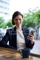 Portrait of businesswoman using mobile phone at counter