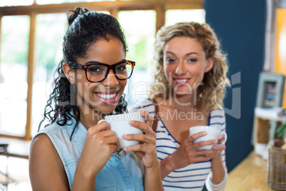 Portrait of female friends smiling while having coffee